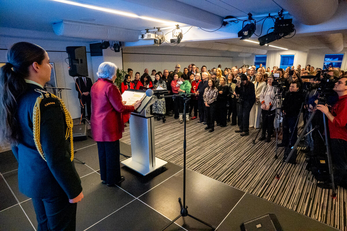 La gouverneure générale Mary Simon s'adresse depuis un podium à un groupe de personnes debout. La photo est prise derrière la gouverneure générale. 