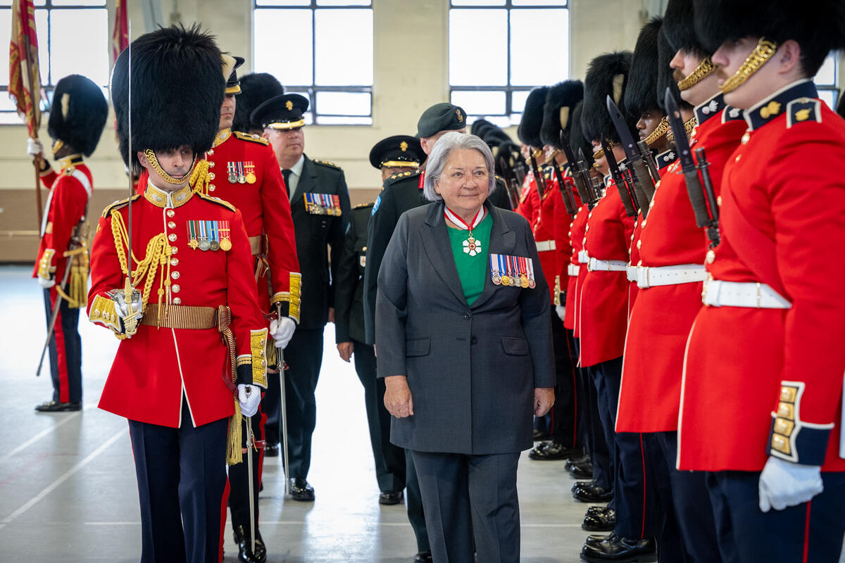 La gouverneure générale Mary Simon passe devant une rangée de soldats des Canadian Grenadier Guards à l'intérieur d'un grand gymnase.