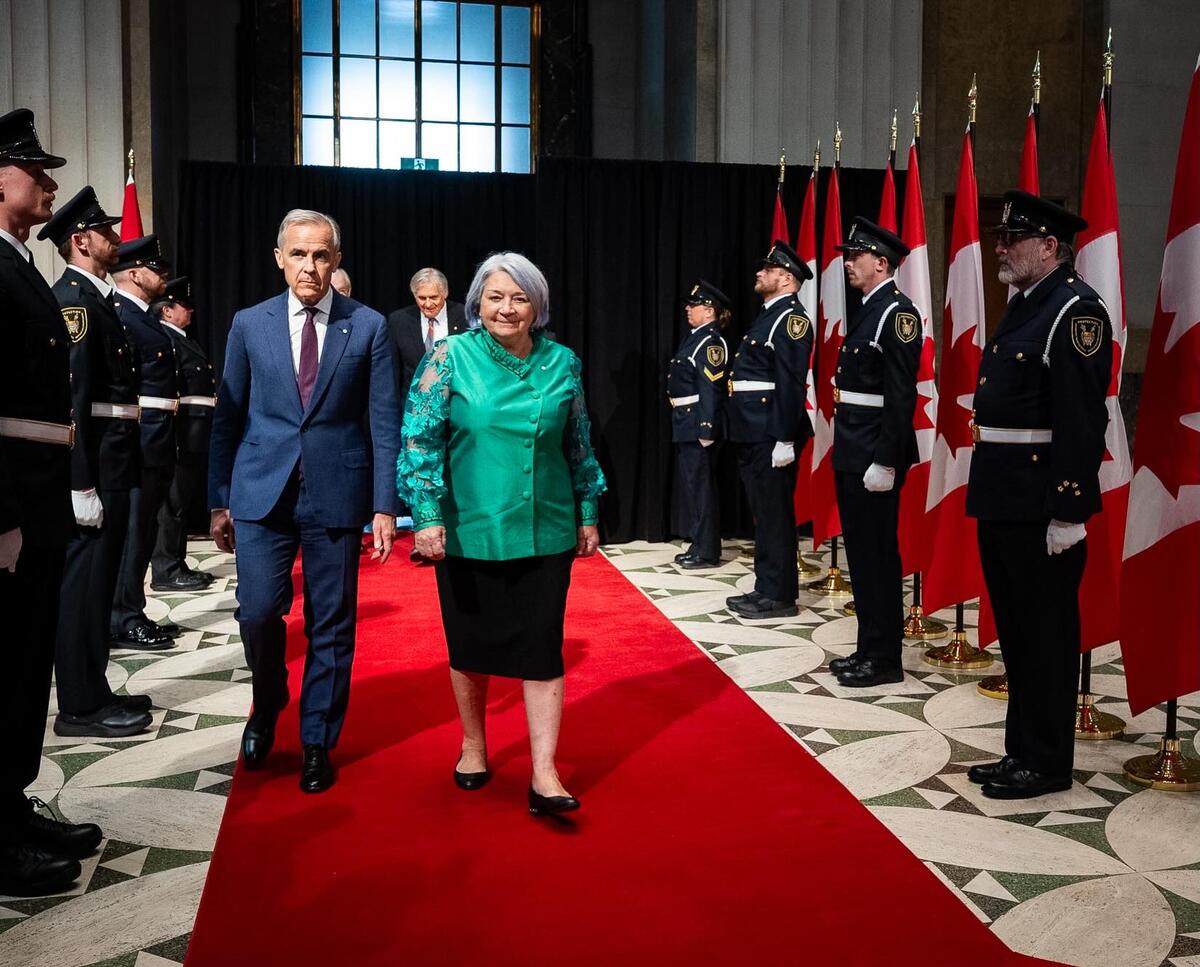 Governor General Mary Simon and Prime Minister Mark Carney walking on a red carpet. 