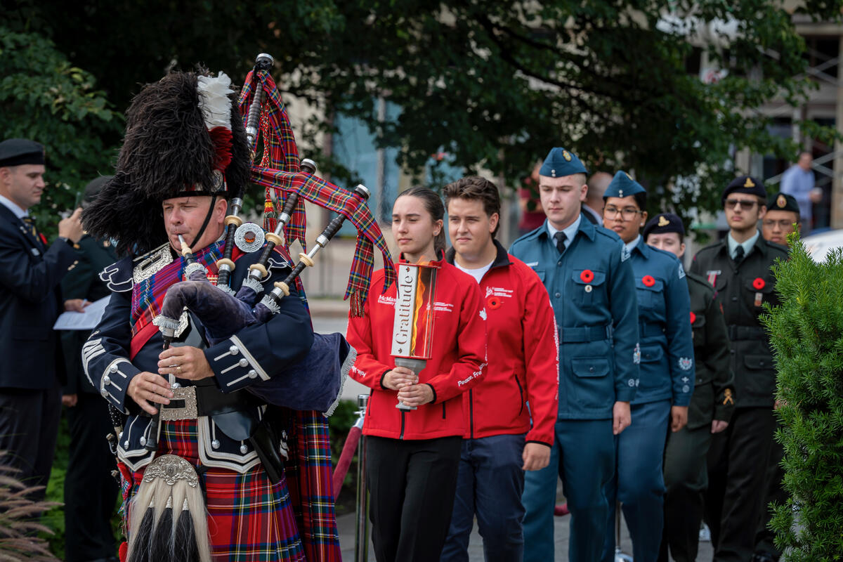 A row of people walking behind a person playing the bagpipes.