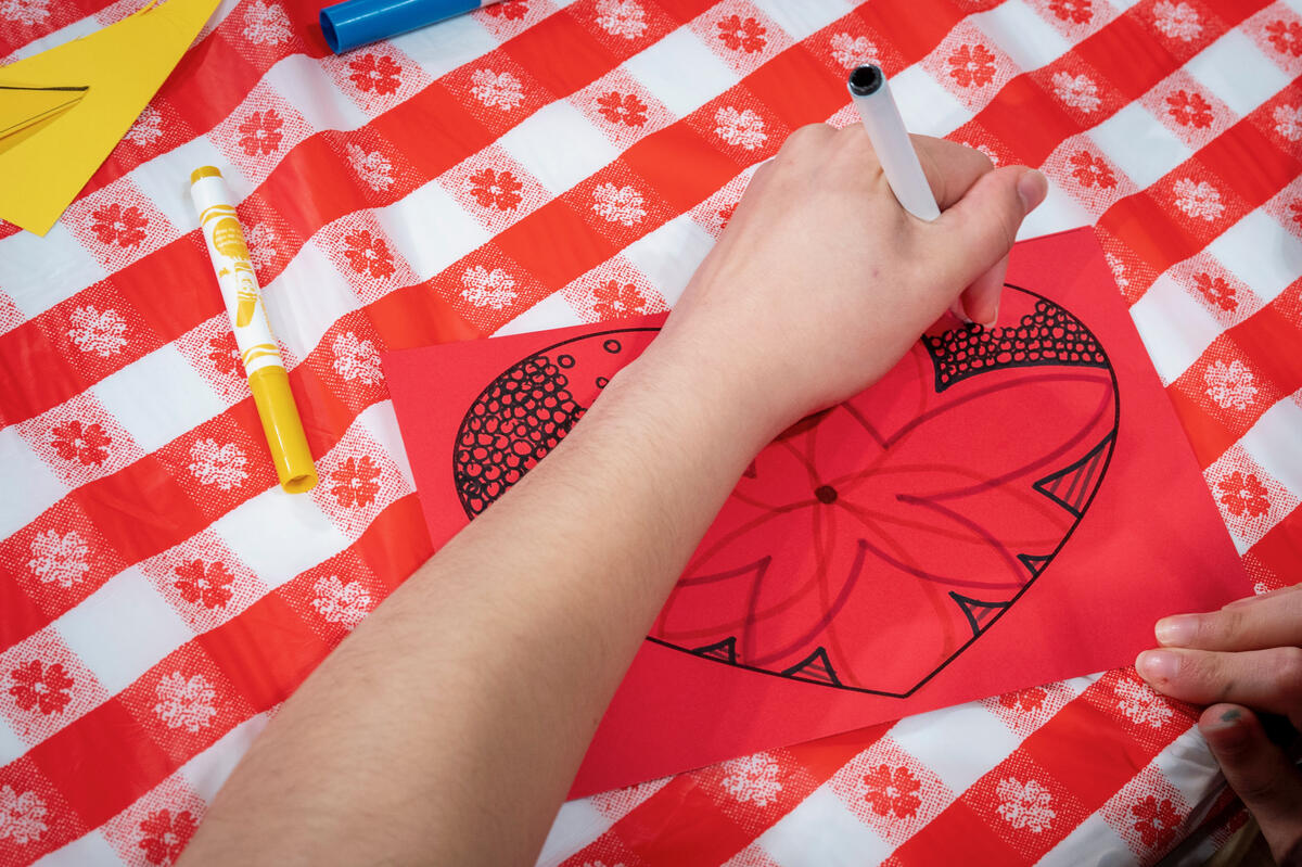 Close-up of a person drawing on a paper heart.