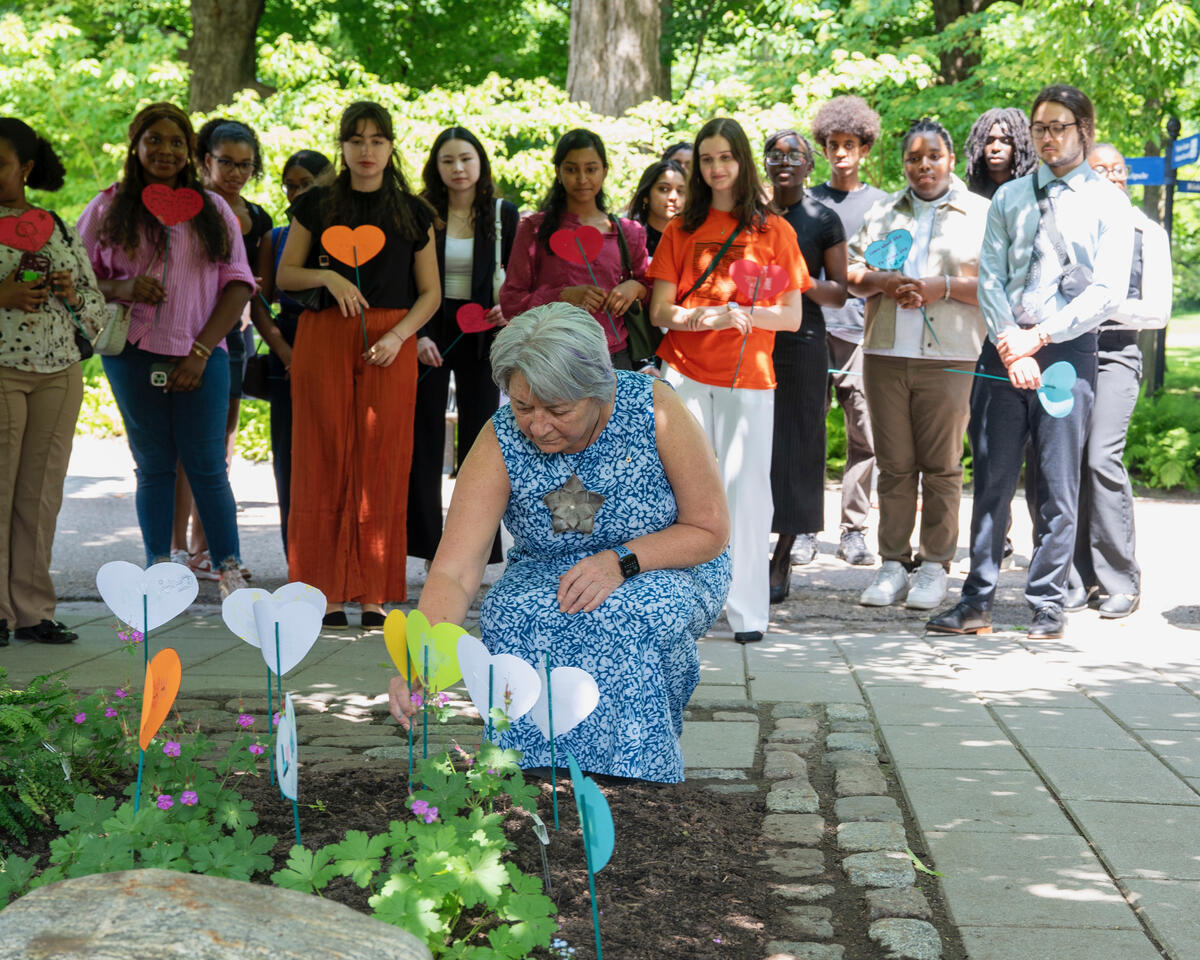Governor General Mary Simon places a paper heart in a heart garden, surrounded by people holding paper hearts.