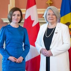 La gouverneure générale Mary Simon se tient à côté de la présidente de la Moldavie, Maia Sandu, à Rideau Hall. Les deux femmes sont souriantes. Un drapeau canadien et un drapeau moldave sont visibles derrière elles.