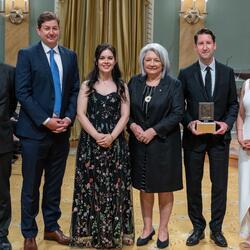 La Gouverneure générale Simon se tient aux côtés d'un groupe de lauréats du Prix Michener. Ils se trouvent dans la salle de bal de Rideau Hall.