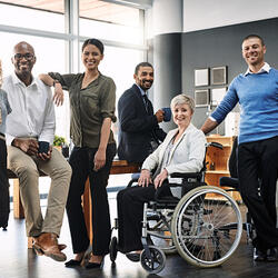 Portrait d'un groupe de personnes dans un bureau. Une dame est en fauteuil roulant.