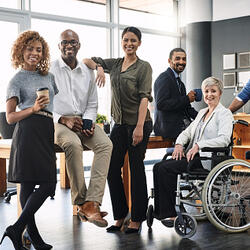 Portrait d'un groupe de personnes dans un bureau. Une personne est en fauteuil roulant.