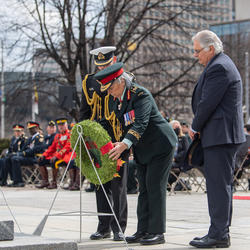 Governor General Simon is laying a wreath at the National War Memorial. Mr. Fraser and a man in a military uniform are standing beside her. 