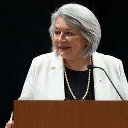 Governor General Simon speaking into a microphone. She is smiling.