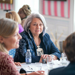 A group of women engage in conversation at a round table with Governor General Simon, in the Tent Room at Rideau Hall. 