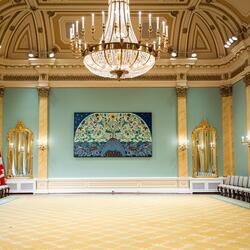 Rideau Hall ballroom. A chandelier hangs from the celing. A large piece of art is on the back wall.