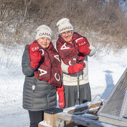 Their Excellencies standing by an outdoor fire, wearing official Olympic mittens, scarves and toques.