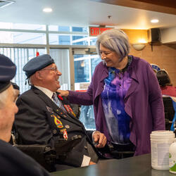 La gouverneure générale Mary Simon s'entretient avec un vétéran de l'Aviation royale canadienne assis dans un fauteuil roulant
