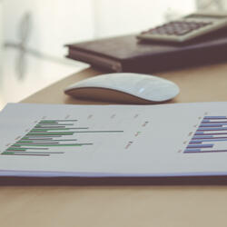 View of a desk that includes a document containing a chart, as well as mouse and keyboard in the background.