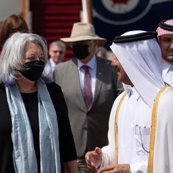 La gouverneure générale (à gauche) parle à un représentant du gouvernement qatari (à droite). On voit un avion à l'arrière-plan.