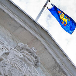 Looking up at the Governor General's flag on top of Rideau Hall. Bright sky with white clouds.