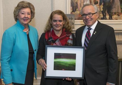 The Governor General holding a photo taken from space, stands in between Their Honours the Honourable Janice C. Filmon, Lieutenant Governor of Manitoba, and the Honourable Gary Albert Filmon