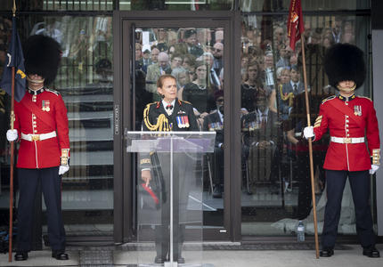 La gouverneure générale prononce une allocution à une tribune, deux gardes de cérémonie se tiennent solennellement de chaque côté.