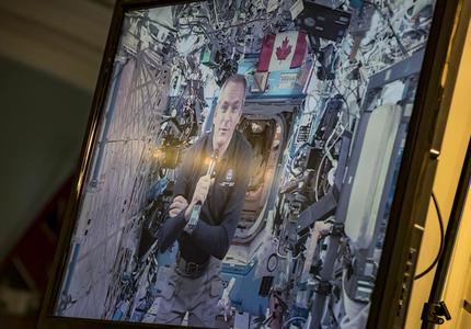 Canadian Space Agency astronaut David Saint-Jacques is on a television screen talking from the International Space Station. 