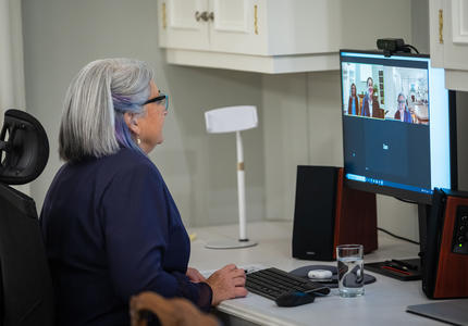 The Governor General participates in a virtual call on her computer. She is sitting at a desk. We can see both her and another woman on her computer screen.