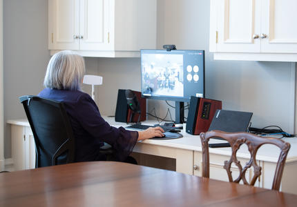 The Governor General is sitting at a computer. She is participating in a virtual event.