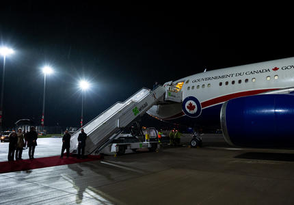 The Government of Canada plane is on the tarmac at the airport. The door to the plane is open and the stairs are open waiting for the passengers to descend. 