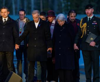 La gouverneure générale Mary Simon, le premier ministre du Canada Mark Carney et le chef du parti de l’opposition officielle du Canada Pierre Poilievre, debout main dans la main. Des personnes se tiennent derrière eux.