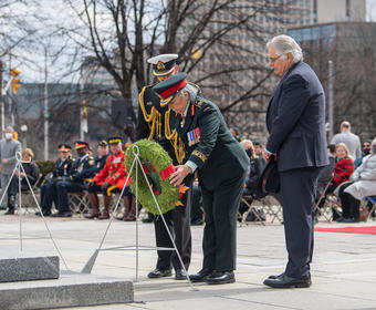 La gouverneure générale Simon dépose une couronne au Monument commémoratif de guerre du Canada. M. Fraser et un homme portant un uniforme militaire sont debout à ses côtés. 
