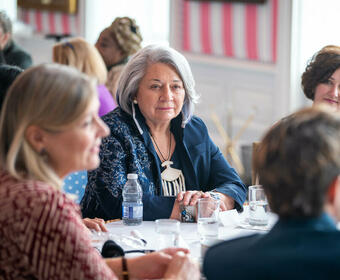 A group of women engage in conversation at a round table with Governor General Simon, in the Tent Room at Rideau Hall. 