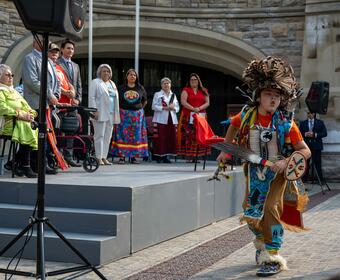 Governor General Marie Simon watches a cultural performance. An indigenous child dances.