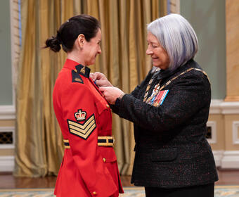 Governor General Mary Simon pins a medal on a member of the Royal Canadian Mounted Police