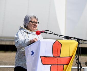 Governor General Mary Simon at at a podium draped in the Nunavut flag