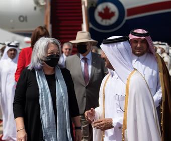 The Governor General (left) talks to a Qatari government official (right). An airplane can be seen in the background.